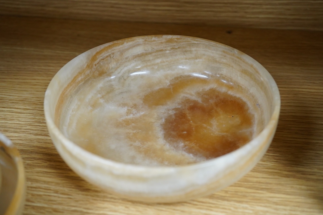 Two petrified wood ashtrays, a malachite rock, three onyx bowls, one with cover, and one other item, larger ashtray 17.5cm wide